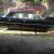 Black 1964  Cadillac 4 door hardtop, w/small fish tails and 4 white wall tires.