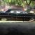 Black 1964  Cadillac 4 door hardtop, w/small fish tails and 4 white wall tires.